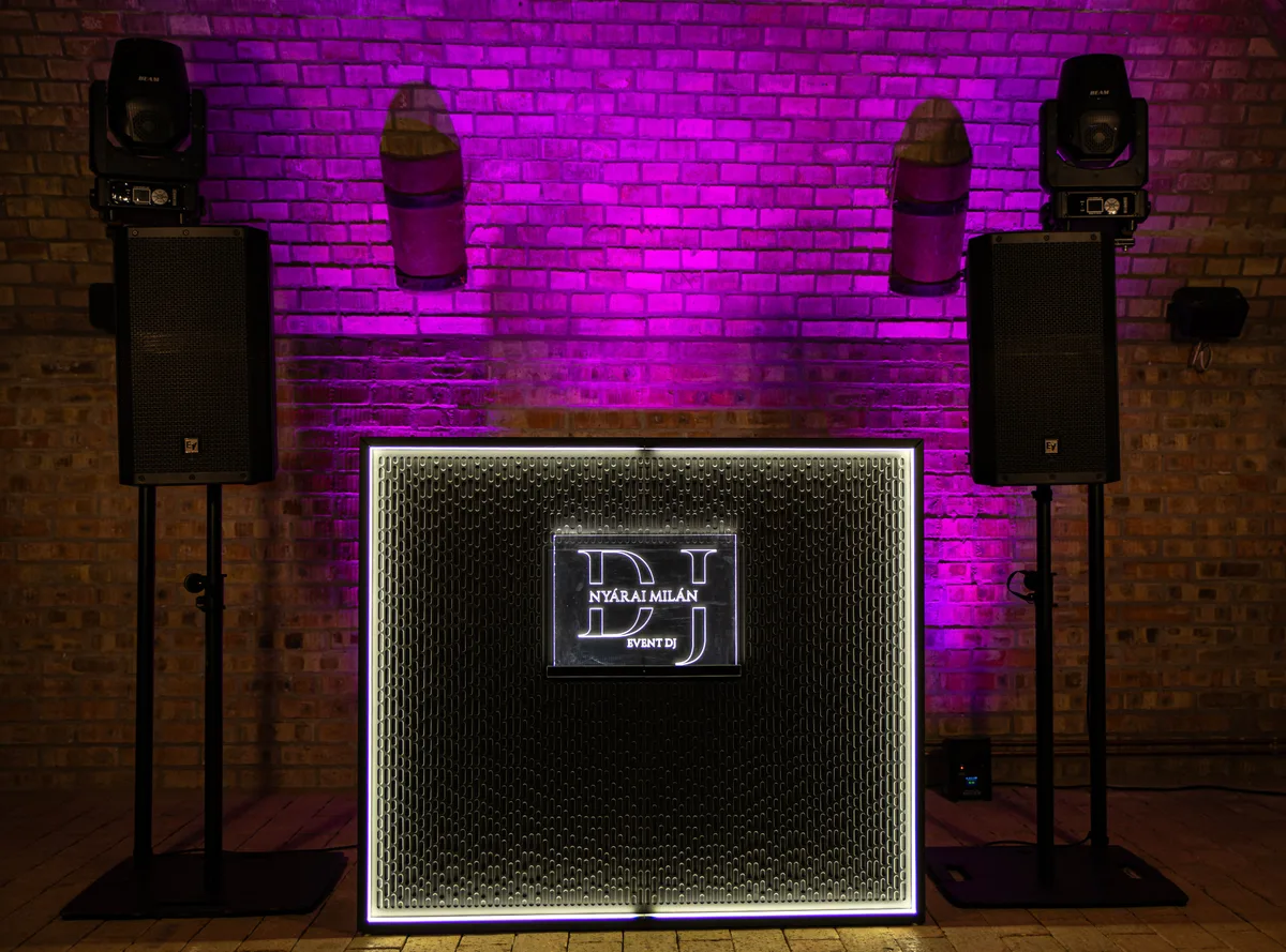 Dark Stereo against a brick wall under purple lighting.